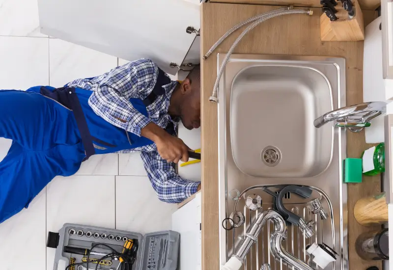 A handyman working to unclog a kitchen sink in Fort Collins, Colorado