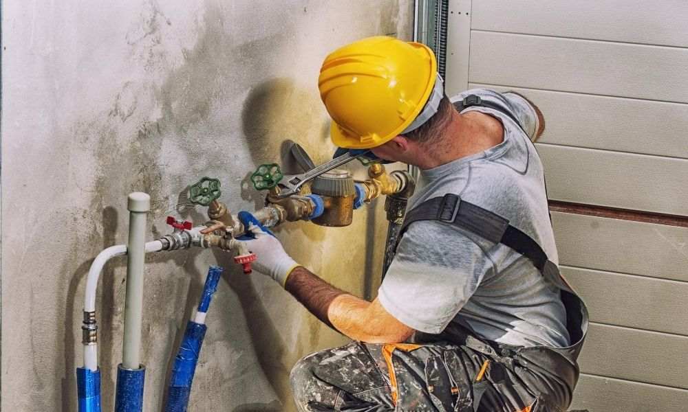 A worker in a safety vest repairs a pipe, highlighting commercial plumbing services in Denver, CO