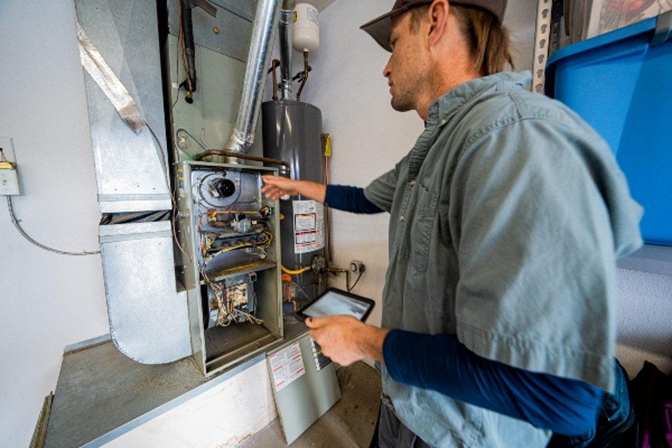 In Fort Collins, CO, a man in a blue shirt inspects the temperature of a furnace for heating repair
