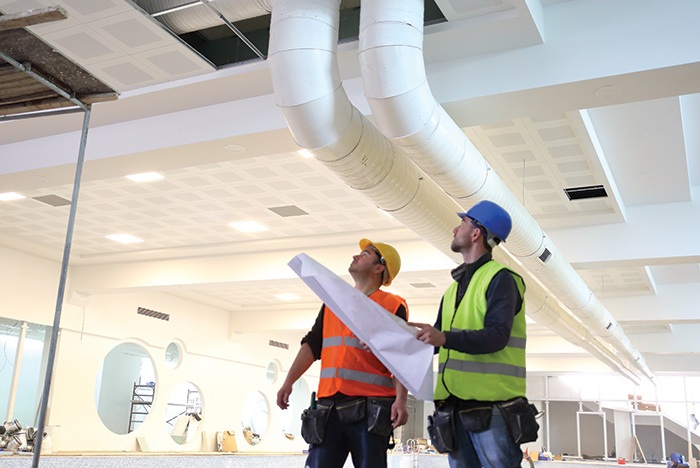 Two HVAC contractors in safety vests, standing in an office building in Fort Collins, CO
