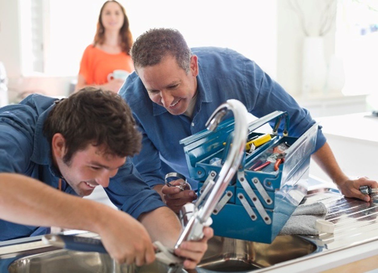 Two men performing plumbing repair services at a kitchen sink in Fort Collins, CO
